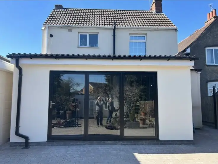 Finished rear extension at a Coventry home with a tiled roof, smooth render and large aluminium sliding doors replacing the old conservatory.