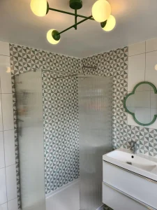 New walk-in shower with textured glass screens and geometric tile wall fitted as part of a bathroom renovation in Bedworth.