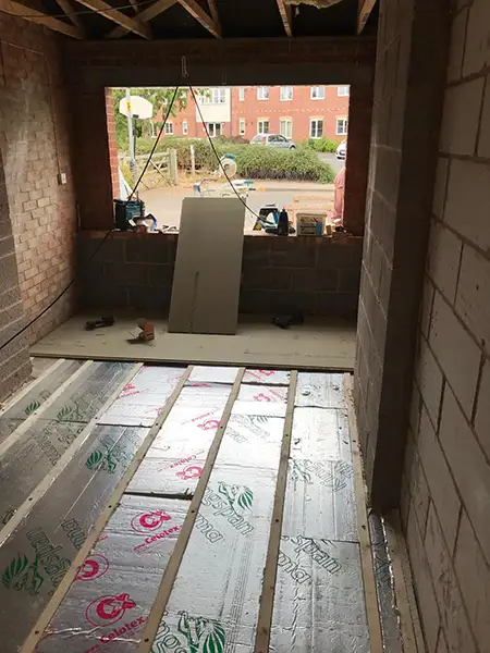 Insulated floor joists installed during a garage conversion in Coventry, showing timber battens and thermal insulation prior to flooring.