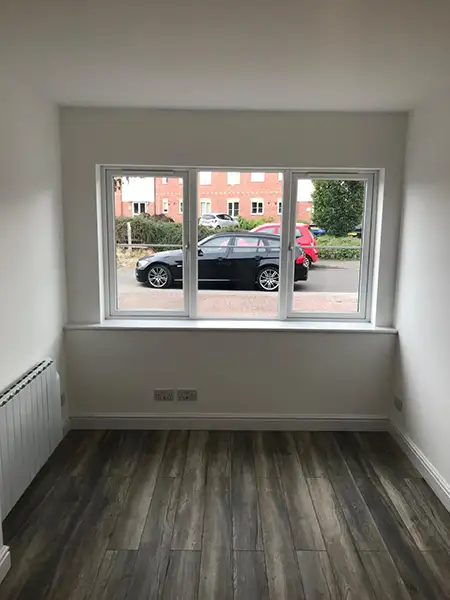 Finished garage conversion interior in a Coventry home, showing a bright newly converted room with modern flooring, fresh white walls and a large front window.