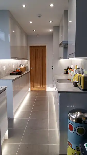 Finished galley-style kitchen formed from a garage conversion in Coventry, showing sleek units, worktops and recessed lighting.
